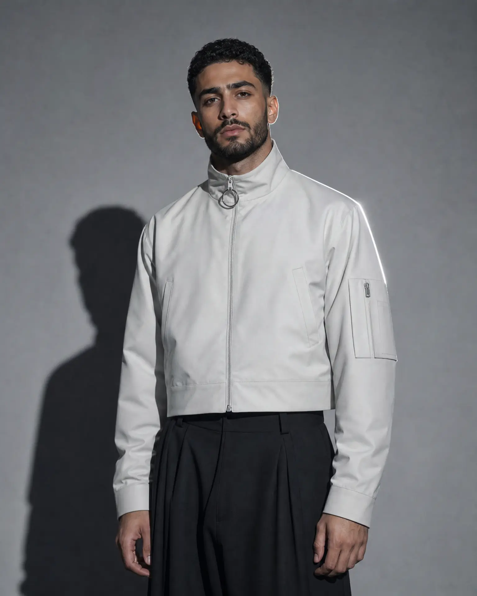 Idris Haddad in a cropped white jacket under directional light